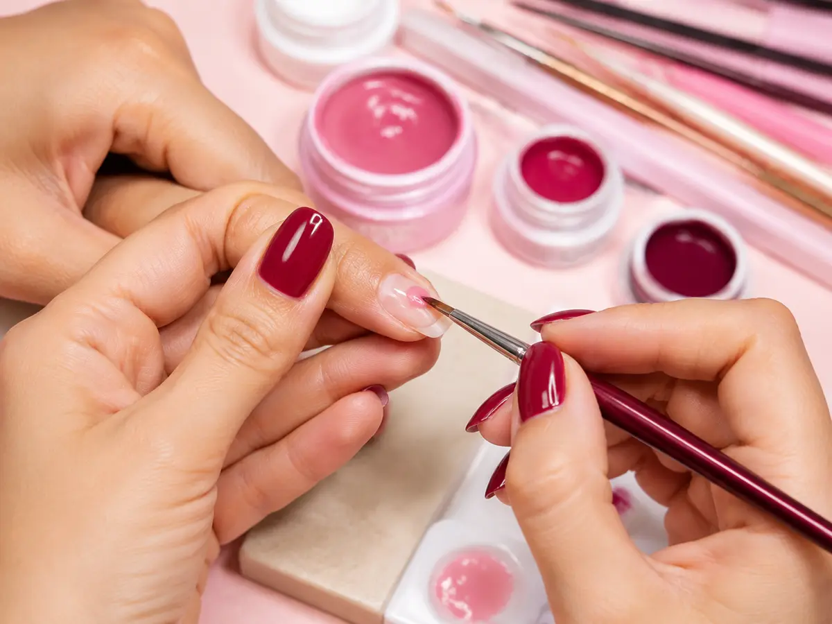 Nail educator demonstrating precise pink gel application